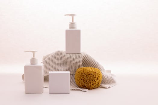 White pump bottles with a natural sponge on a textured cloth, ideal for beauty product mockups.